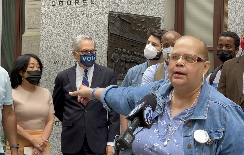 Mrs Dee Dee speaks into a 6 ABC mic while pointing to Larry Krasner and Helen Gym