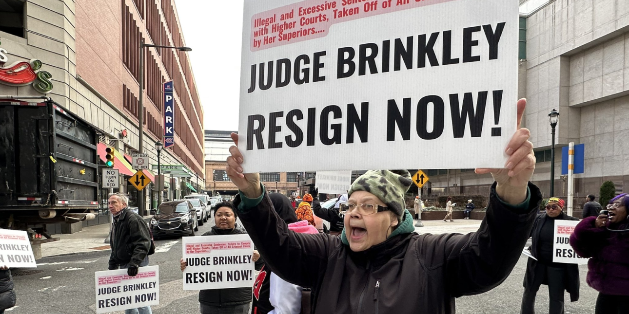 protesters hold signs calling for the resignation of Judge Genece Brinkley