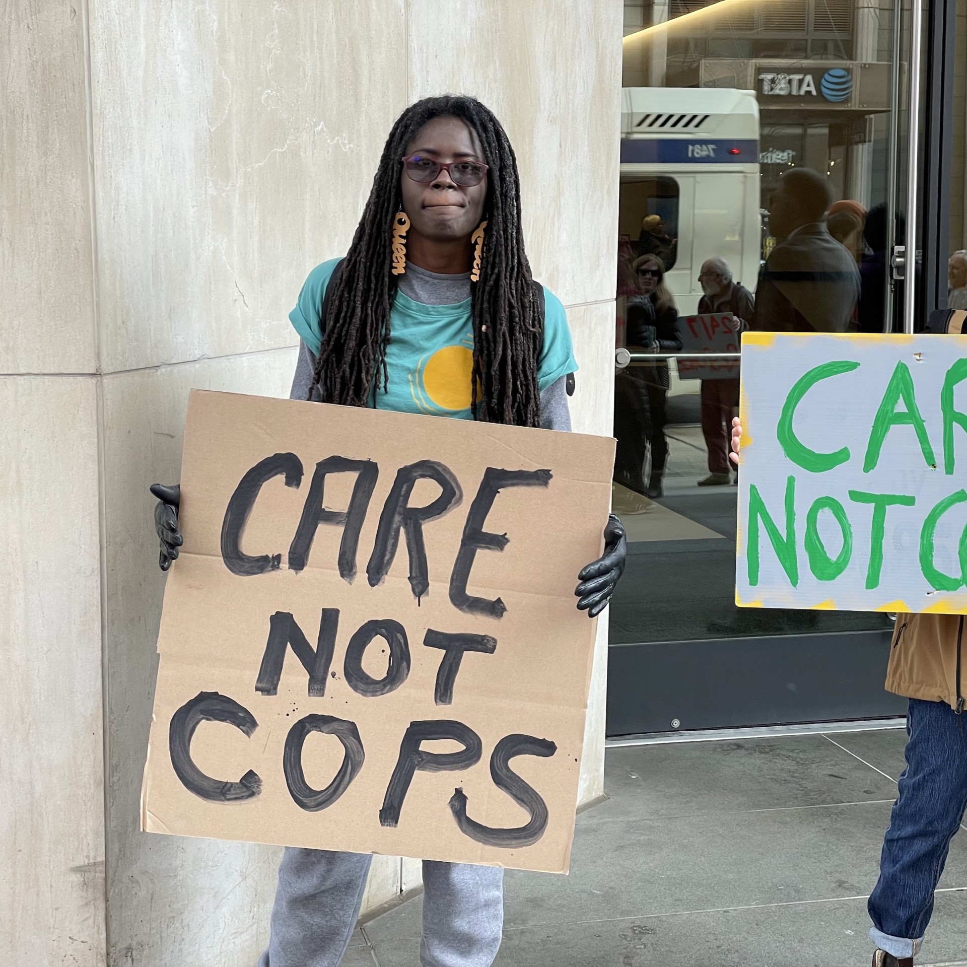 Two people hold signs that read 'Care Not Cops'