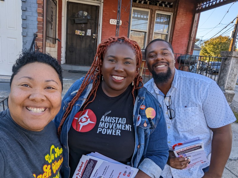 Nikki, Derrick, and Kris smiling on the street doing GOTV on Election Day eve