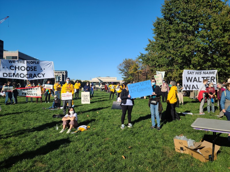 people gathered holding signs "We the People Choose Democracy" and "Say His Name Walter Wallace" prominently featured